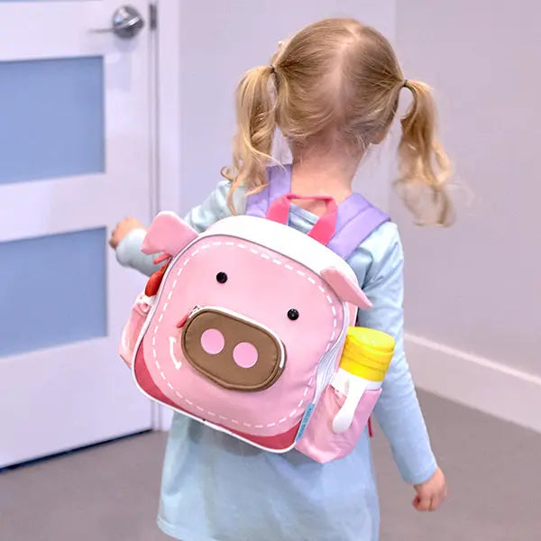 Marcus & Marcus Insulated Backpack in pink pig design with yellow bottle holder, worn by a girl walking away.