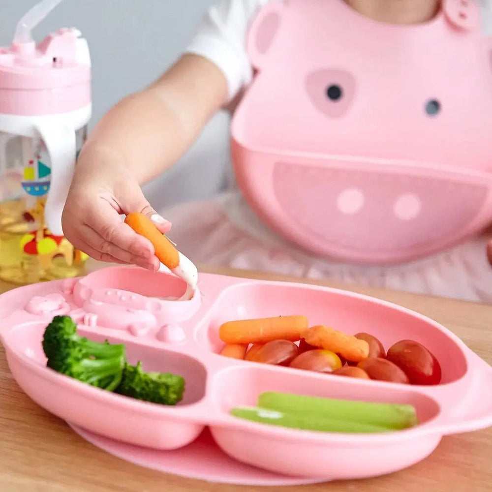 Marcus & Marcus Yummy Dips Suction Divided Plate in pink; toddler dips carrot into a section.