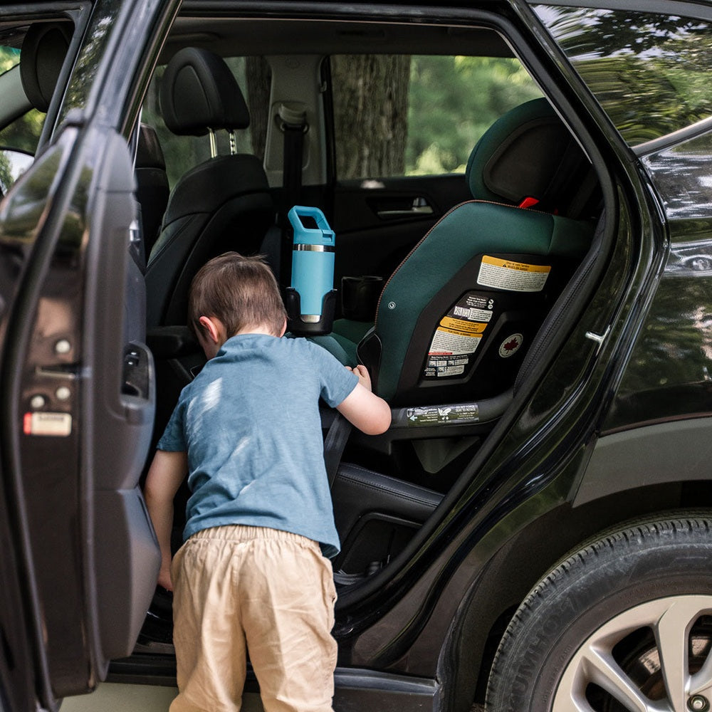 MAXI COSI Andi 360 rotating convertible car seat in teal/green installed in SUV; child approaching nearby