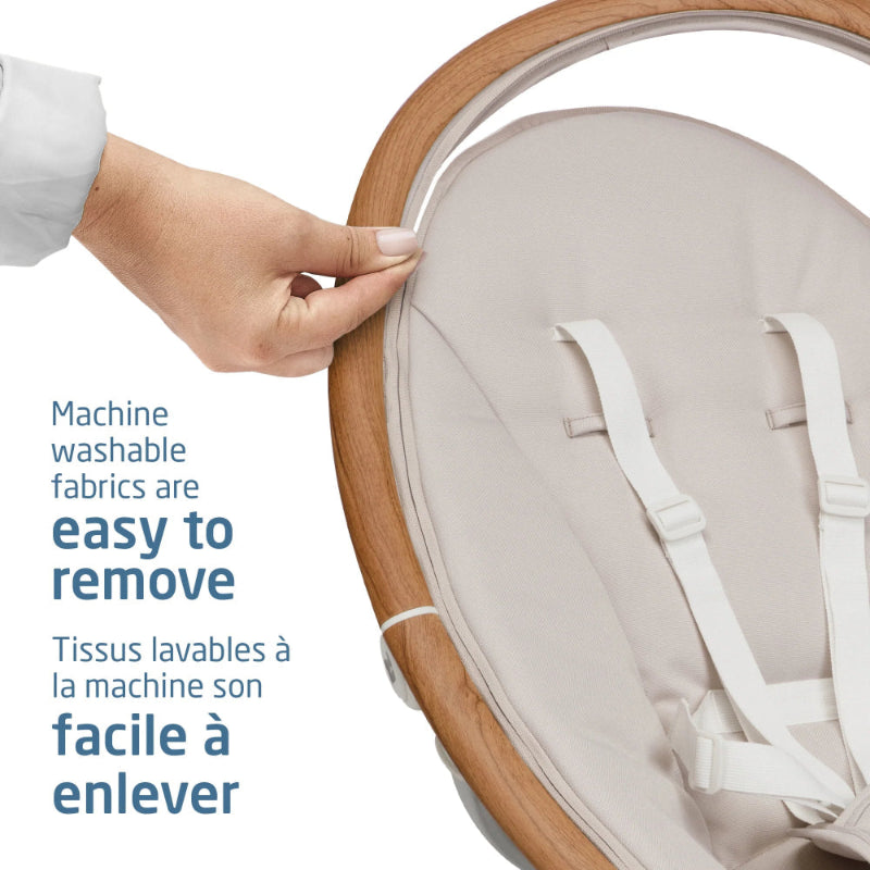Maxi Cosi Cassia Swing with beige fabric; a hand lifts the removable cover from the wooden frame.