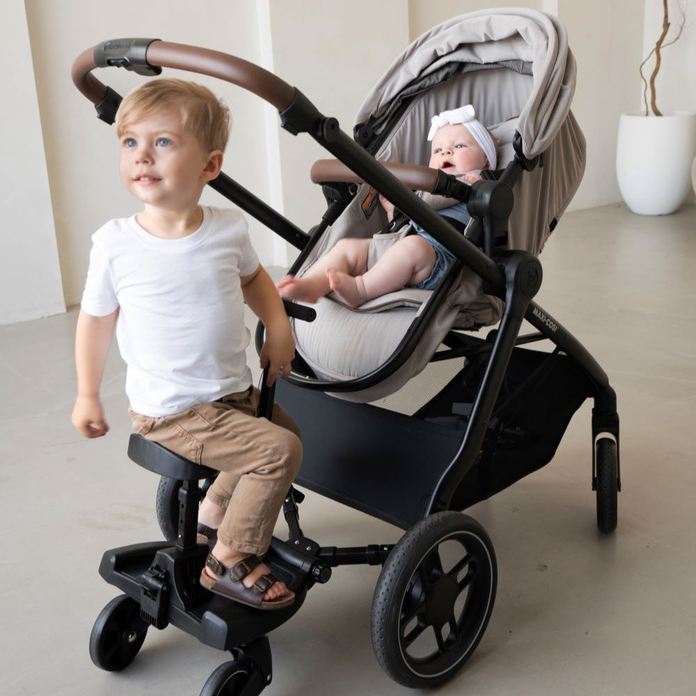 Maxi Cosi Hop-on Board attached to stroller; toddler standing on board, baby seated in the carriage.