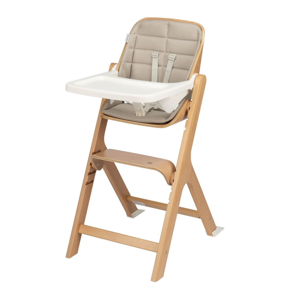 Maxi-Cosi Nesta 3-In-1 High Chair, natural wood frame with beige cushion, white tray attached for mealtime.