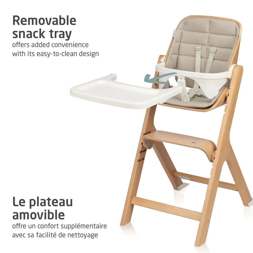 Maxi Cosi Nesta 3-In-1 High Chair with removable white snack tray extended for meals, beige cushioned seat, wooden frame.