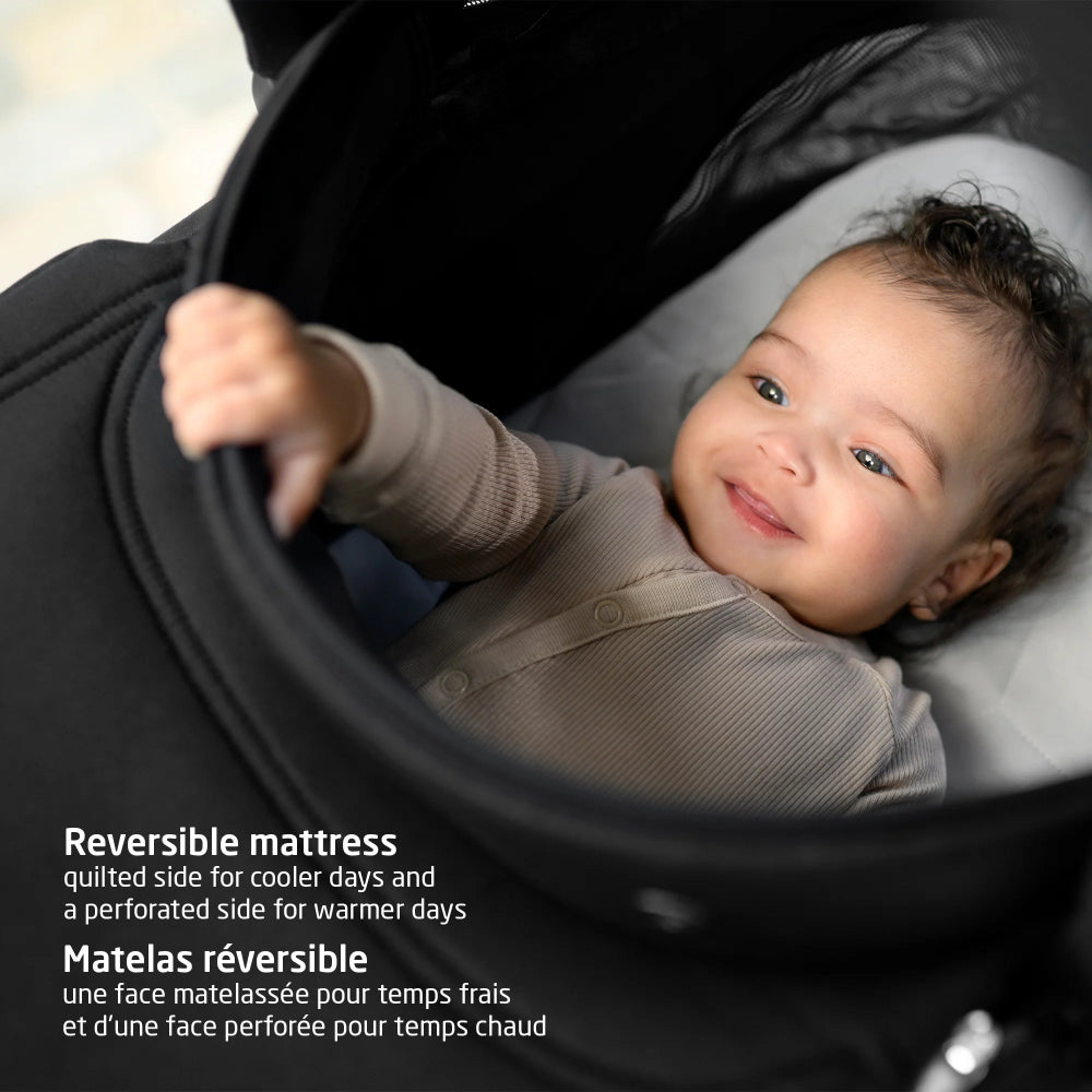 MAXI COSI Oria2 carrycot in Twillic Black with a smiling baby inside