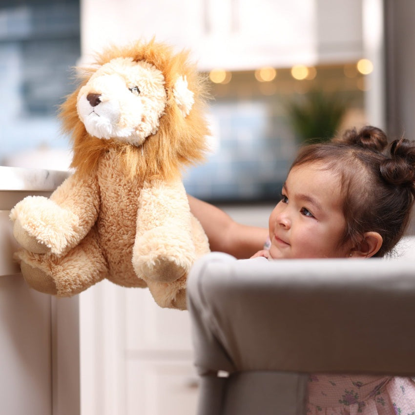 MAXI COSI Swift Playard baby bassinet setup with a plush lion toy in a bright kitchen