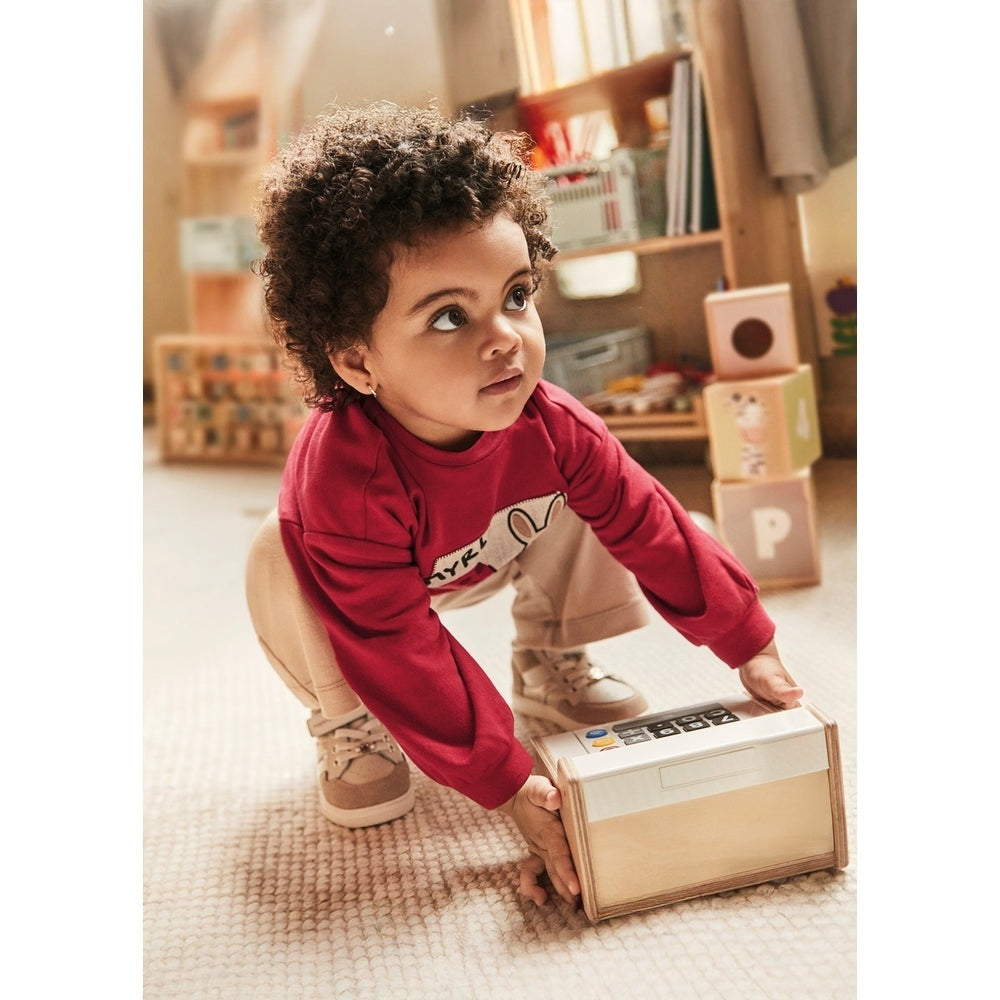 Mayoral Baby Pants and Sweater Set Red, toddler girl in red top and beige pants crouches to lift a wooden toy box.