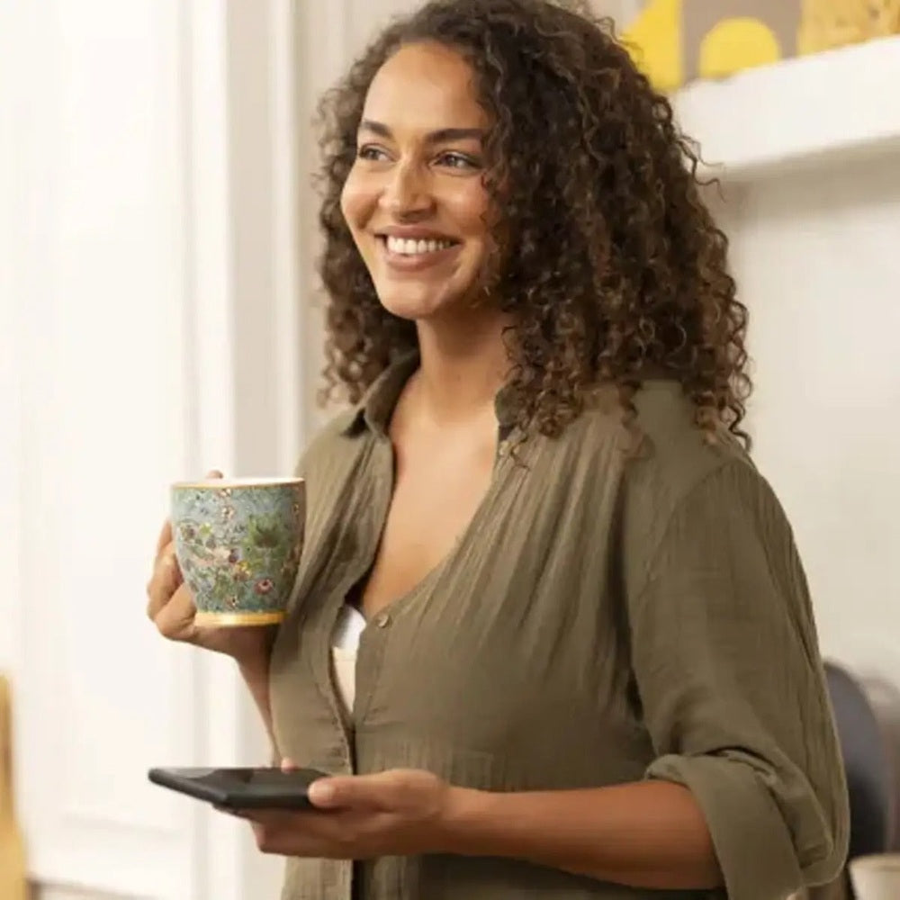 MEDELA Melody InBra Double Electric Breast Pump user smiling at home, holding mug.