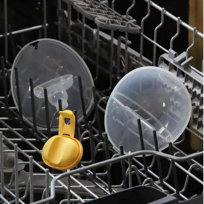 Medela Motion Inbra Double Electric Breast Pump parts drying in dishwasher; yellow valve and clear flanges visible.