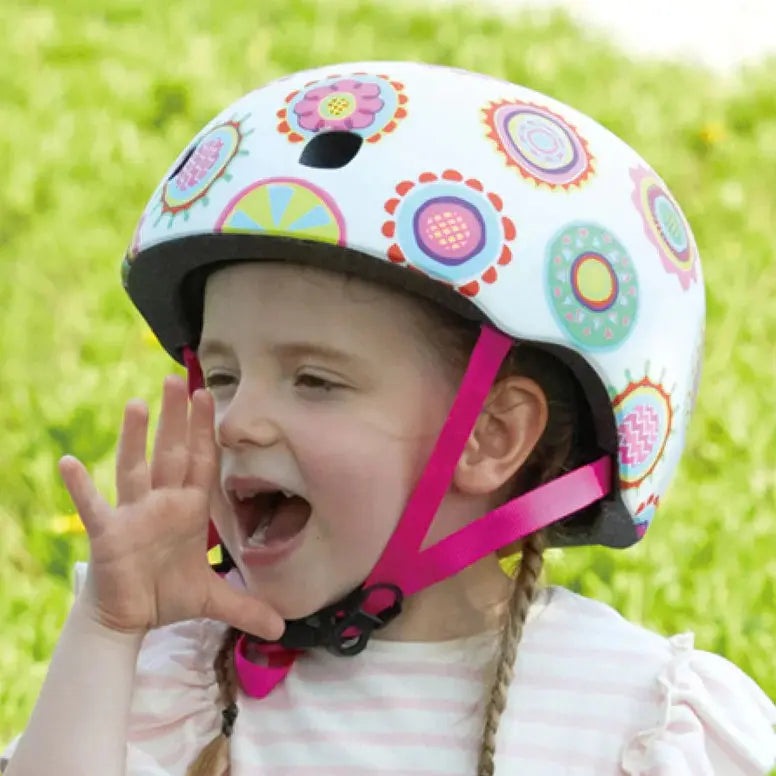 Micro Helmet V2 Doodle Dot worn by a smiling child outdoors, pink chin straps securing the colorful helmet.