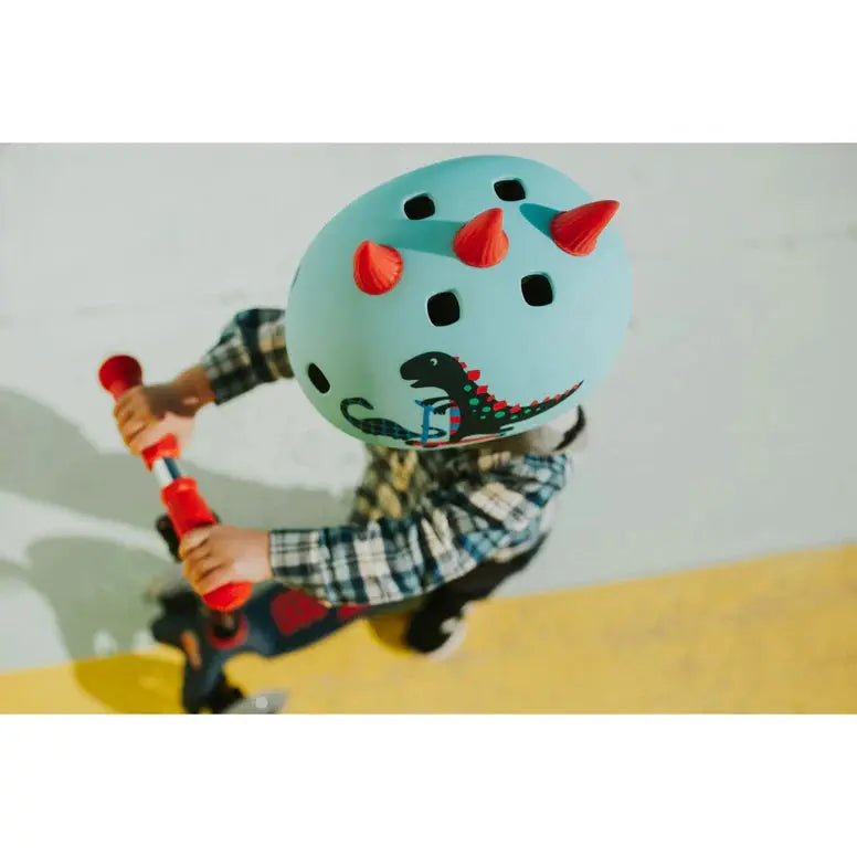 Micro Helmet V2 Dragon helmet in light blue with red horns worn by child riding a scooter, dragon graphic.