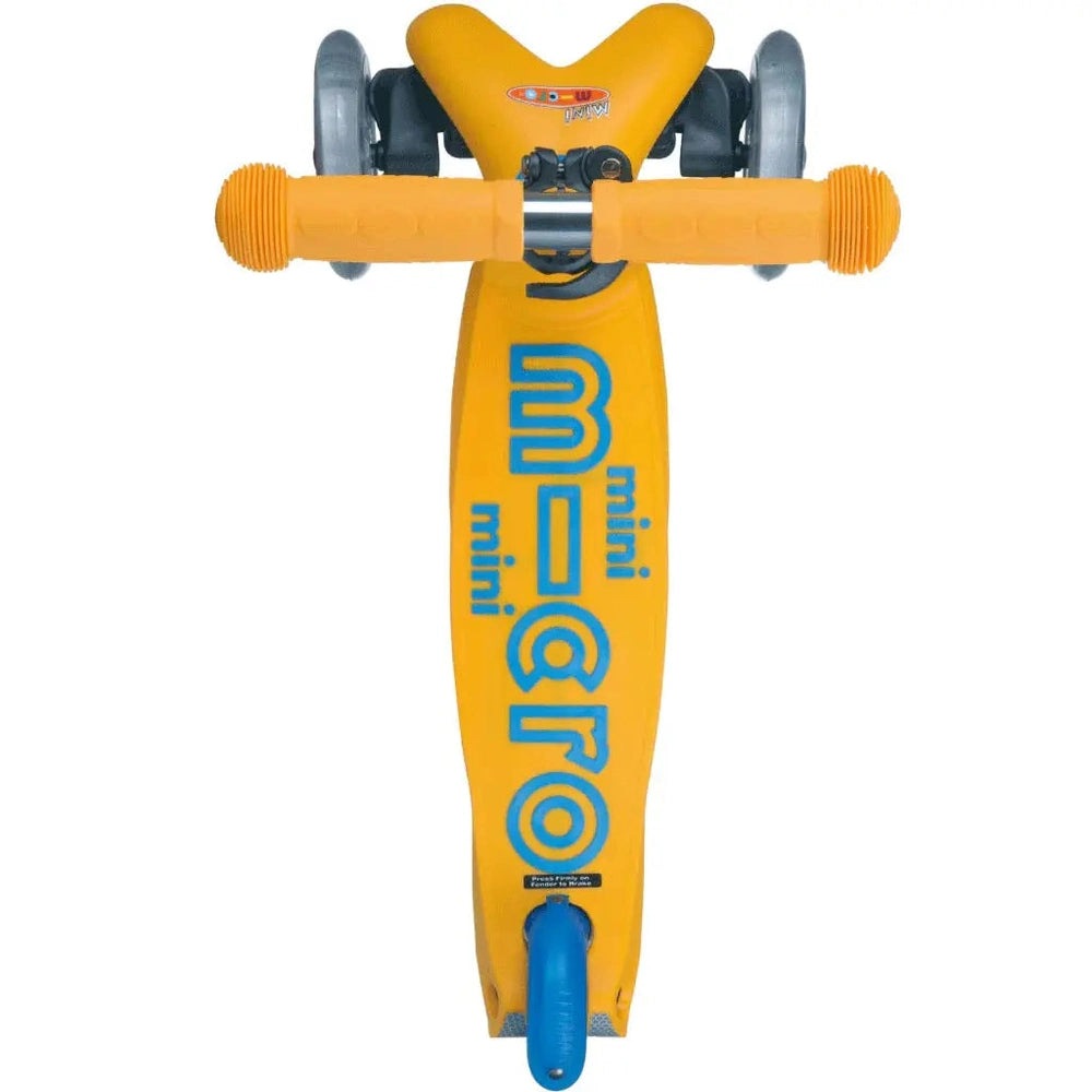 Micro Mini Deluxe Scooter in bright yellow with blue branding, orange grip handlebars, and blue wheels ready to ride.
