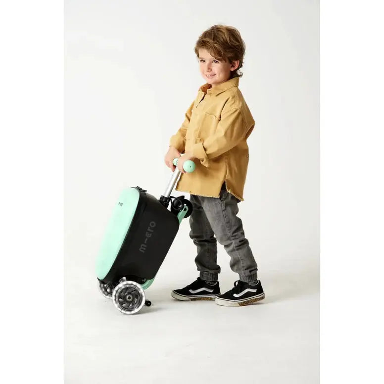 Micro Scooter Junior Luggage Mint suitcase in mint with wheels; child pushes it along using the extendable handle.