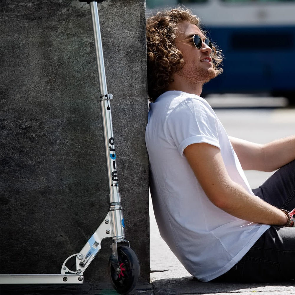 Micro Speed Scooter Pure Silver aluminum frame with large front wheel, MICRO brand, outdoor urban scene