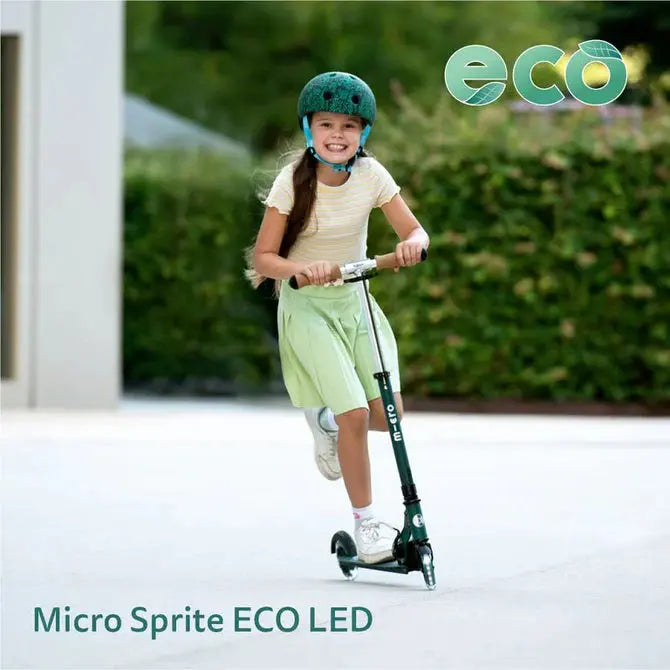 Micro Sprite LED Scooter; girl glides on a green LED scooter outdoors, wearing a teal helmet.