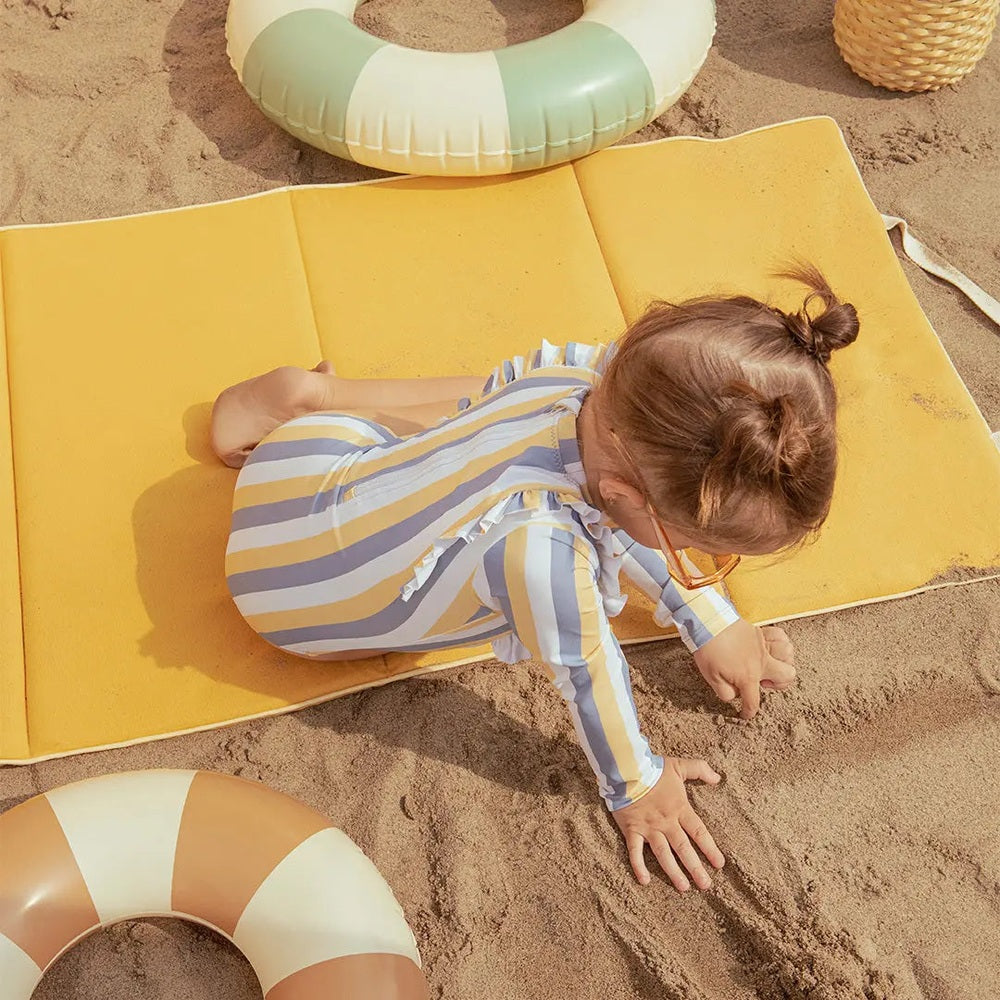 Miles The Label Sunrise & Blue Striped Long-Sleeve One-Piece Swimsuit worn by a child playing in sand on a yellow mat