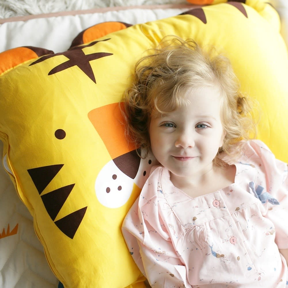 Milo & Gabby kids pillowcase on a bright yellow monster-print pillow with a smiling child