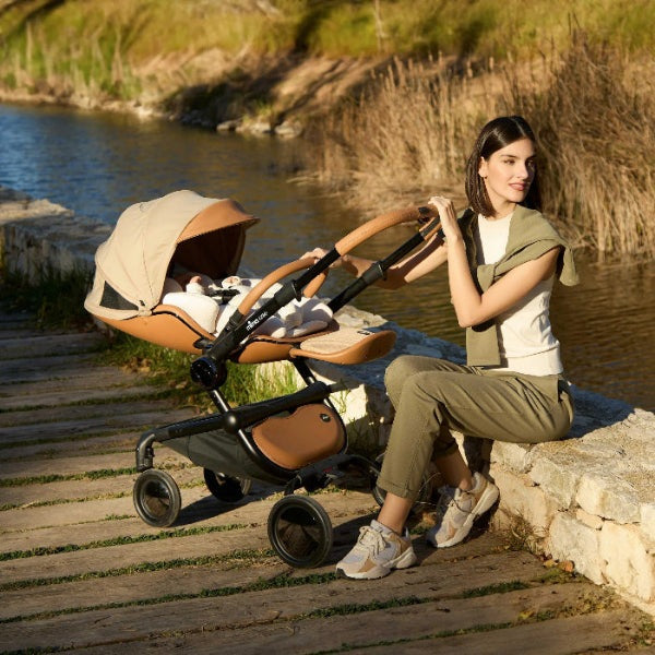 Mima Creo Newborn Snuggle stroller accessory in tan leather on a baby stroller by the water