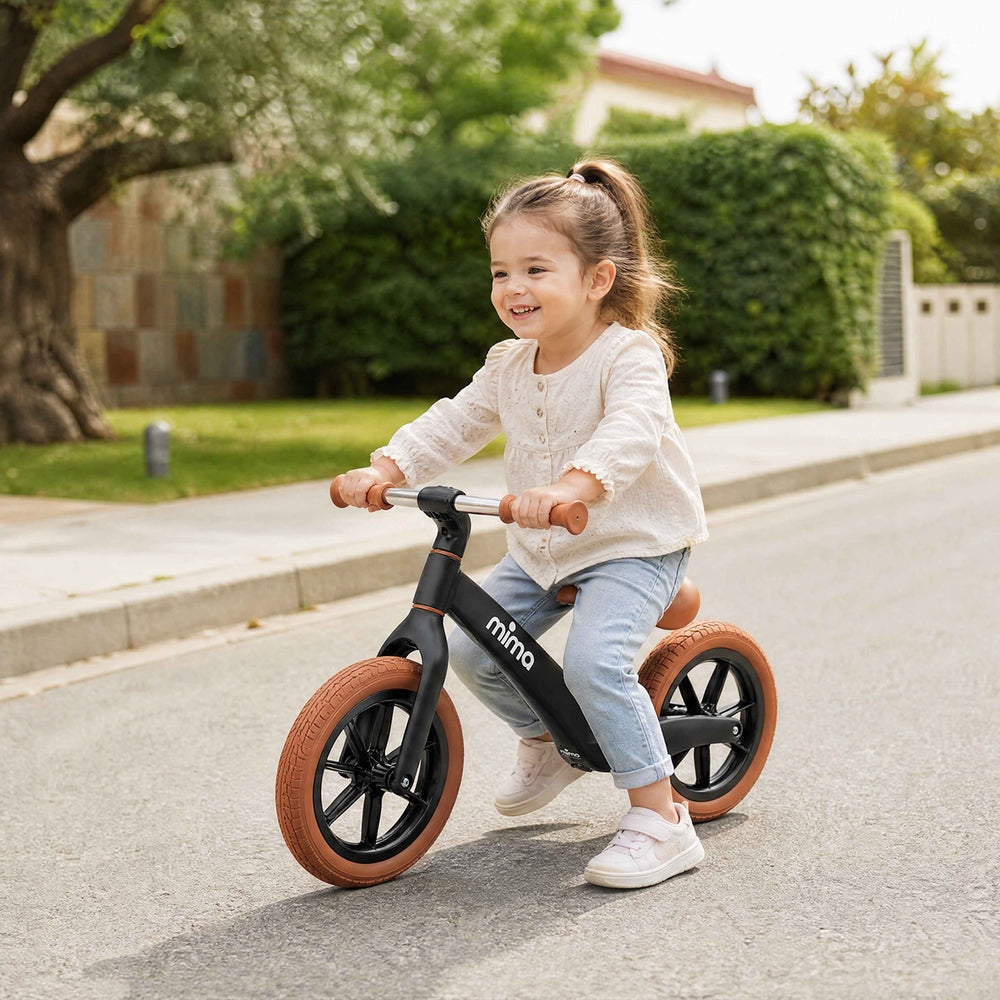 Mima Zoom Lite Balance Bike in Black toddler riding outdoors