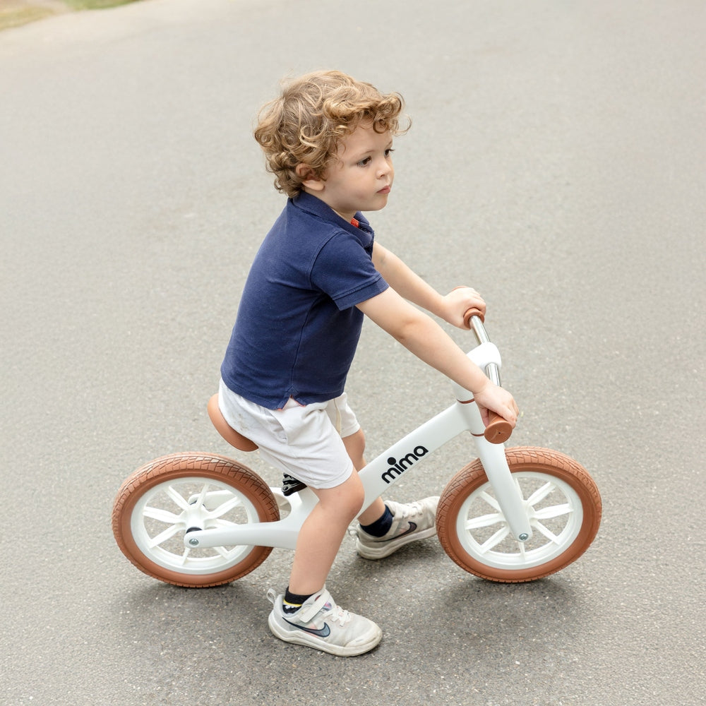 Mima Zoom Lite Balance Bike in White toddler riding outdoors