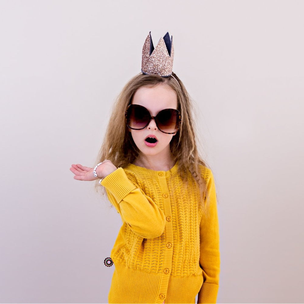 Mimi & Lula glitter crown Alice Gold on a girl wearing a mustard cardigan and oversized sunglasses