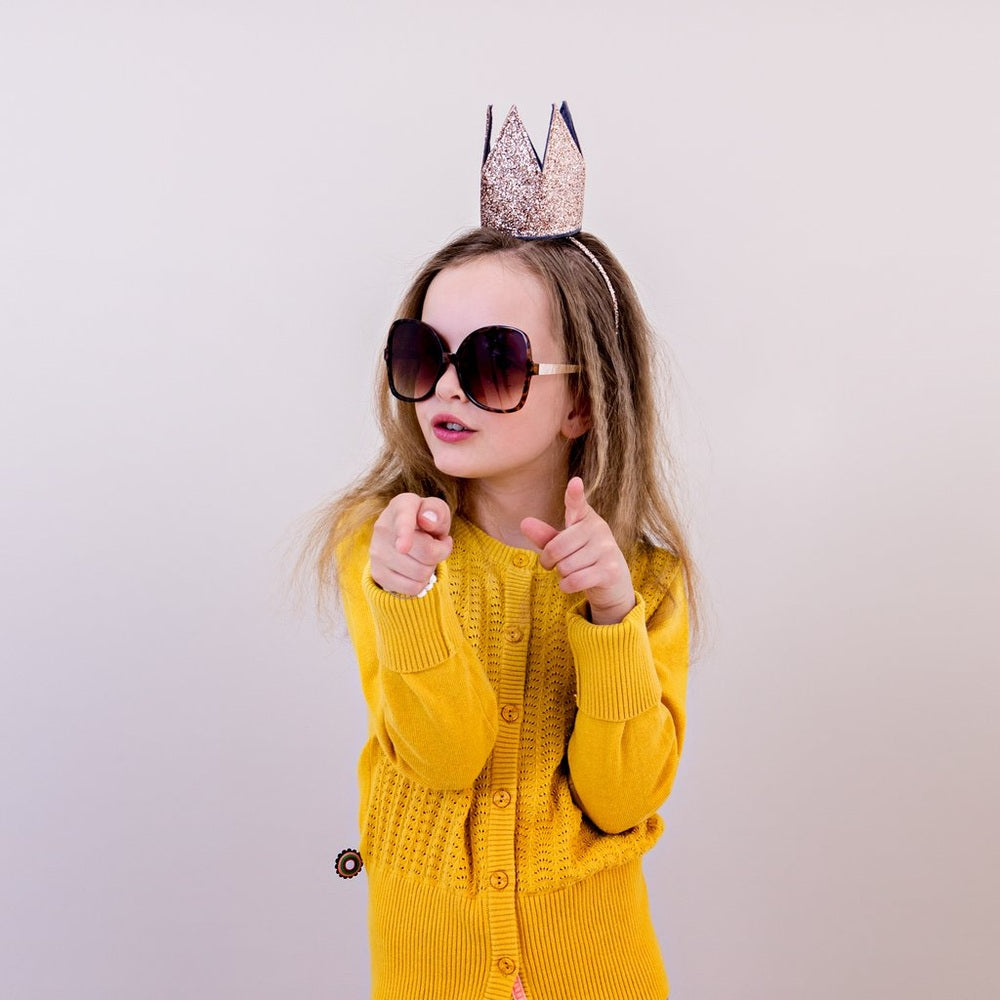 Mimi & Lula Glitter Crown Alice Gold worn by child with oversized sunglasses and a yellow cardigan