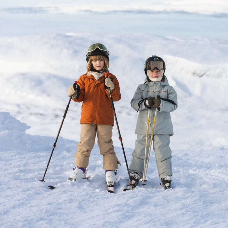 Mini A Ture Matadane Ski Tech Jacket Grs Quarry worn by two kids in orange and gray outerwear, posing with ski poles in the snow.