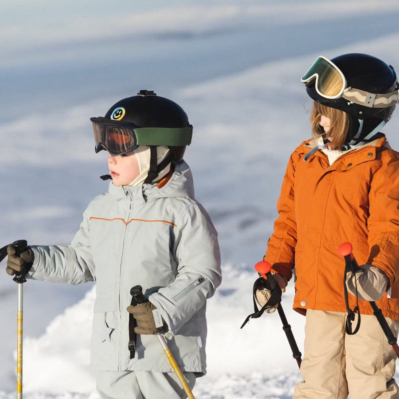 MINI A TURE Matadane Ski Tech Jacket Grs Quarry worn by two kids in orange/gray on a snowy slope, holding ski poles.