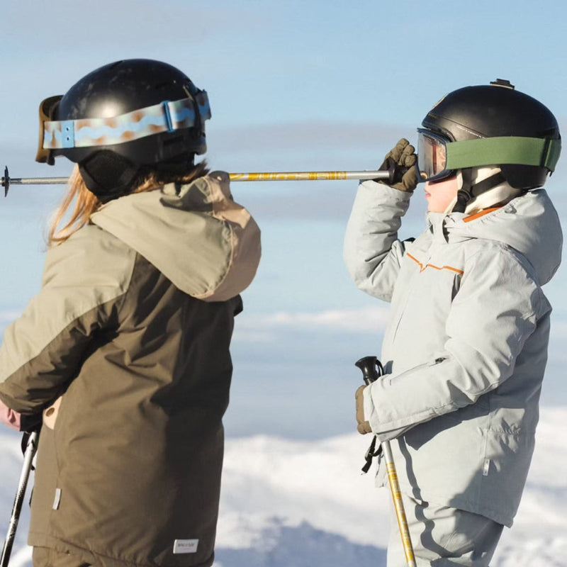 Mini A Ture Matadane Ski Tech Jacket Grs Quarry worn by skiers on a snowy slope as they connect ski poles.