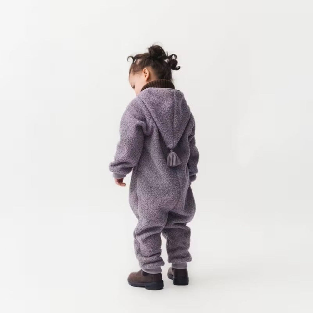 MINI A TURE Matadel teddyfleece jumpsuit for toddlers in zinc purple, hood with tassel, paired with brown boots