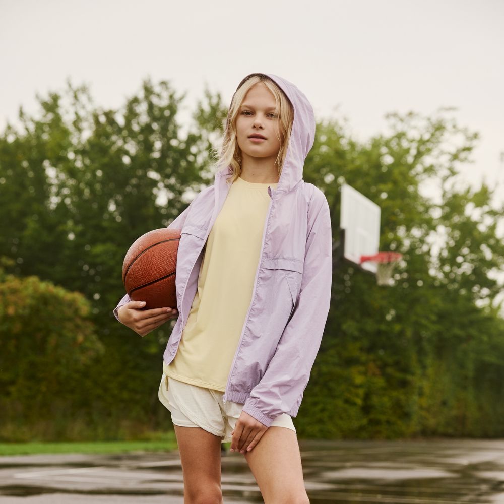 MINI A TURE Matasla UV Jacket GRS Thistle lavender hooded jacket worn by girl with hood up, holding a basketball.