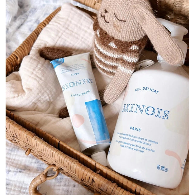 Minois Paris Essentials Gift Box with white gel bottle and blue-accented tube in a wicker basket