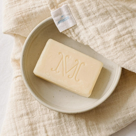 Minois Paris Gentle Soap bar in ivory on a ceramic dish with beige linen cloth