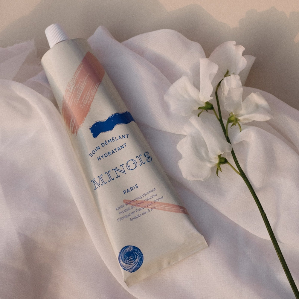 Minois Paris hydrating detangling conditioner, 180 ml bottle with pink and blue accents on white fabric