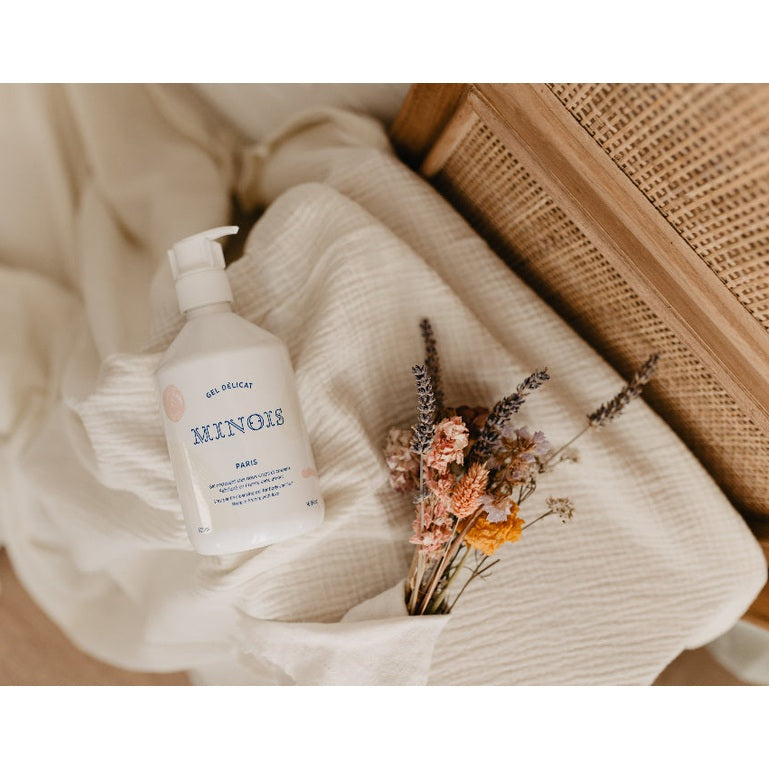 Minois Paris washing gel for body and hair, white 500 ml bottle with pump beside dried flowers.