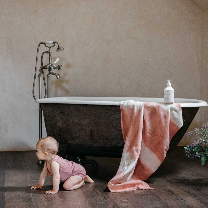 MINOIS PARIS Washing Gel for body and hair, 500 ml, bottle on vintage black bathtub with pink towel.