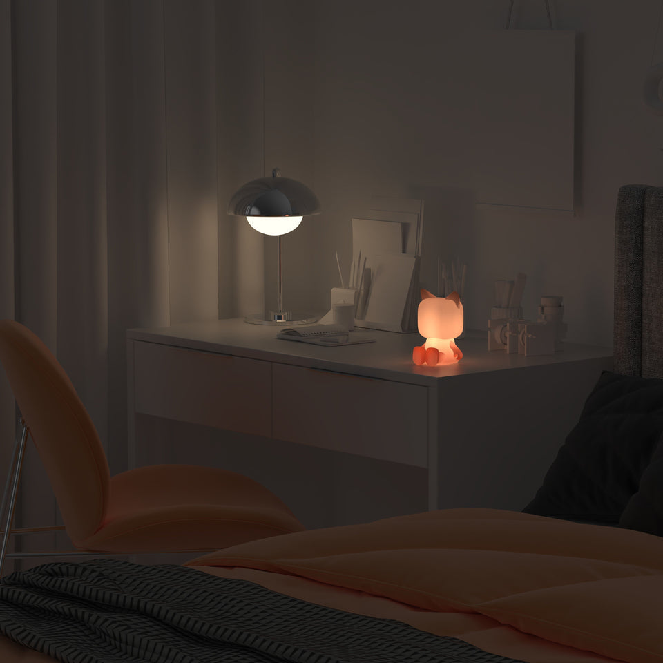 Mob Animal Light cat-shaped night light by MOB on a white desk with warm orange glow