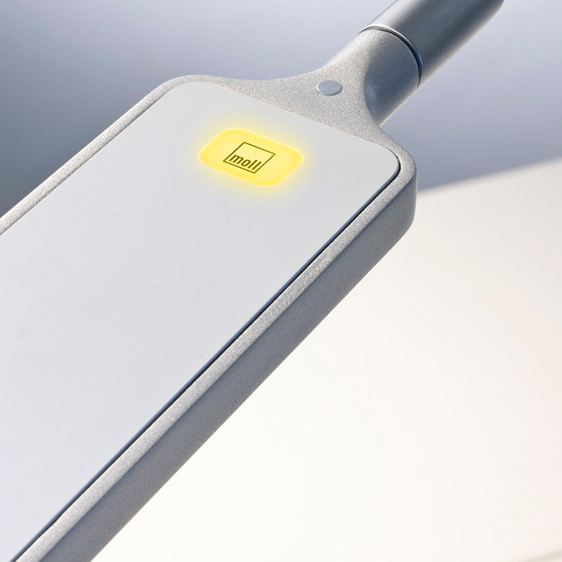Moll FlexLight desk lamp with metallic gray body and yellow power button for studying