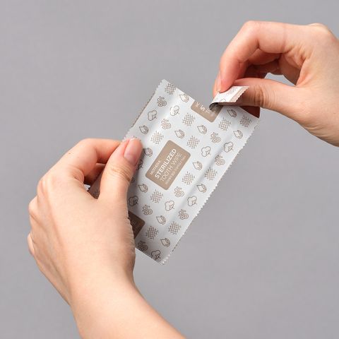 Mother-K sterilized tooth wipe packet being opened; grey patterned packaging for baby health