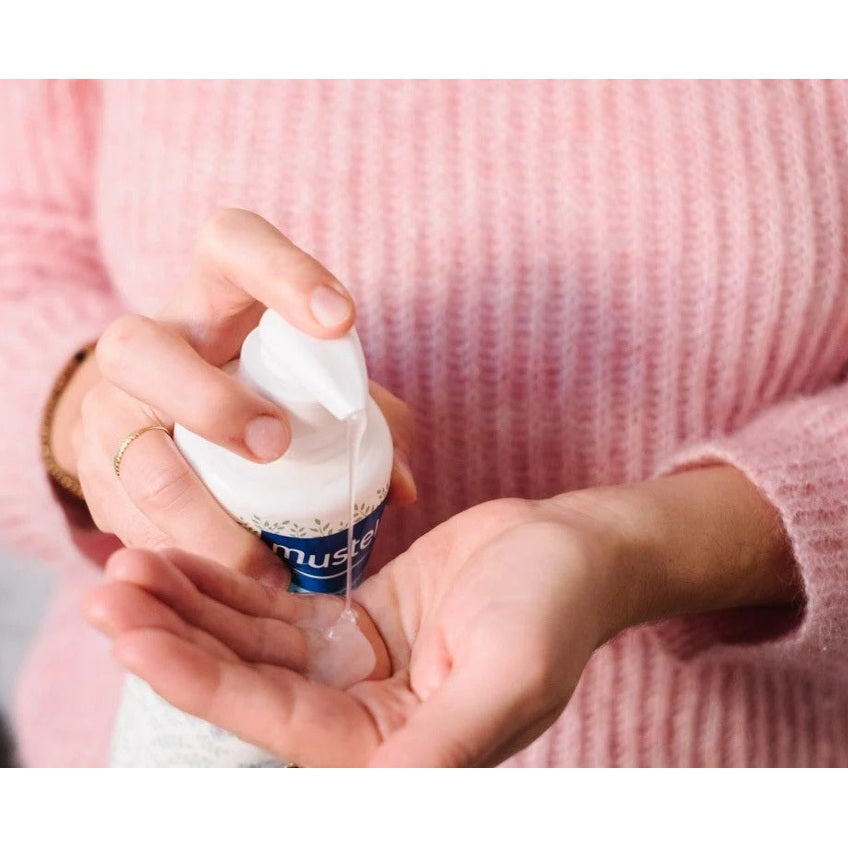 Mustela 2 In 1 Cleansing Gel With Avocado 500 ml being squeezed into the palm of a person in a pink sweater.