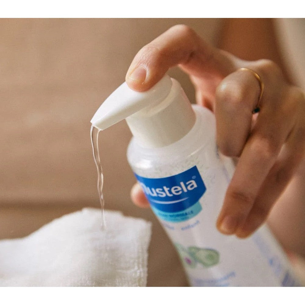 Mustela Baby Cleansing Water with Organic Avocado 300 ml, pump bottle dispenses cleansing liquid onto cloth.
