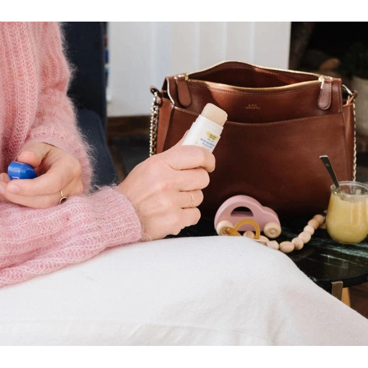 Mustela Nourishing Cold Cream Stick 9.2g held in hand beside a pink knit sweater