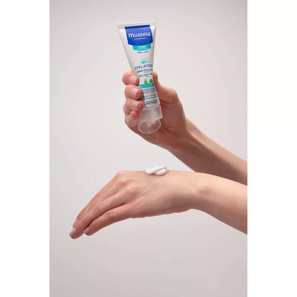 Mustela Stelatopia Emollient Facial Cream 40 ml being squeezed onto the back of a hand