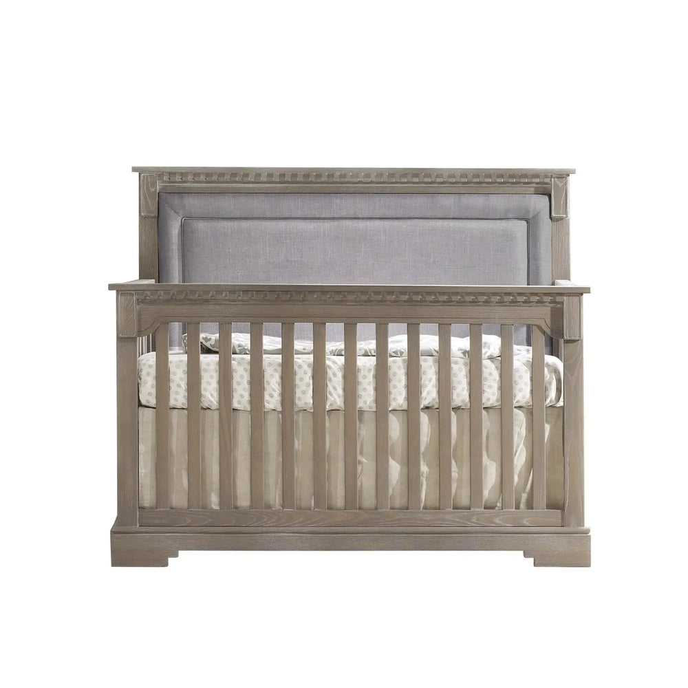 Natart Ithaca 5-In-1 Convertible Crib With Upholstered Headboard Panel in gray wood finish, showing slatted sides.