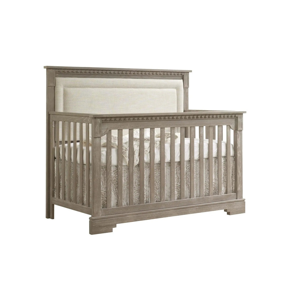 Natart Ithaca 5-in-1 Convertible Crib with upholstered headboard in a graywashed wood finish.