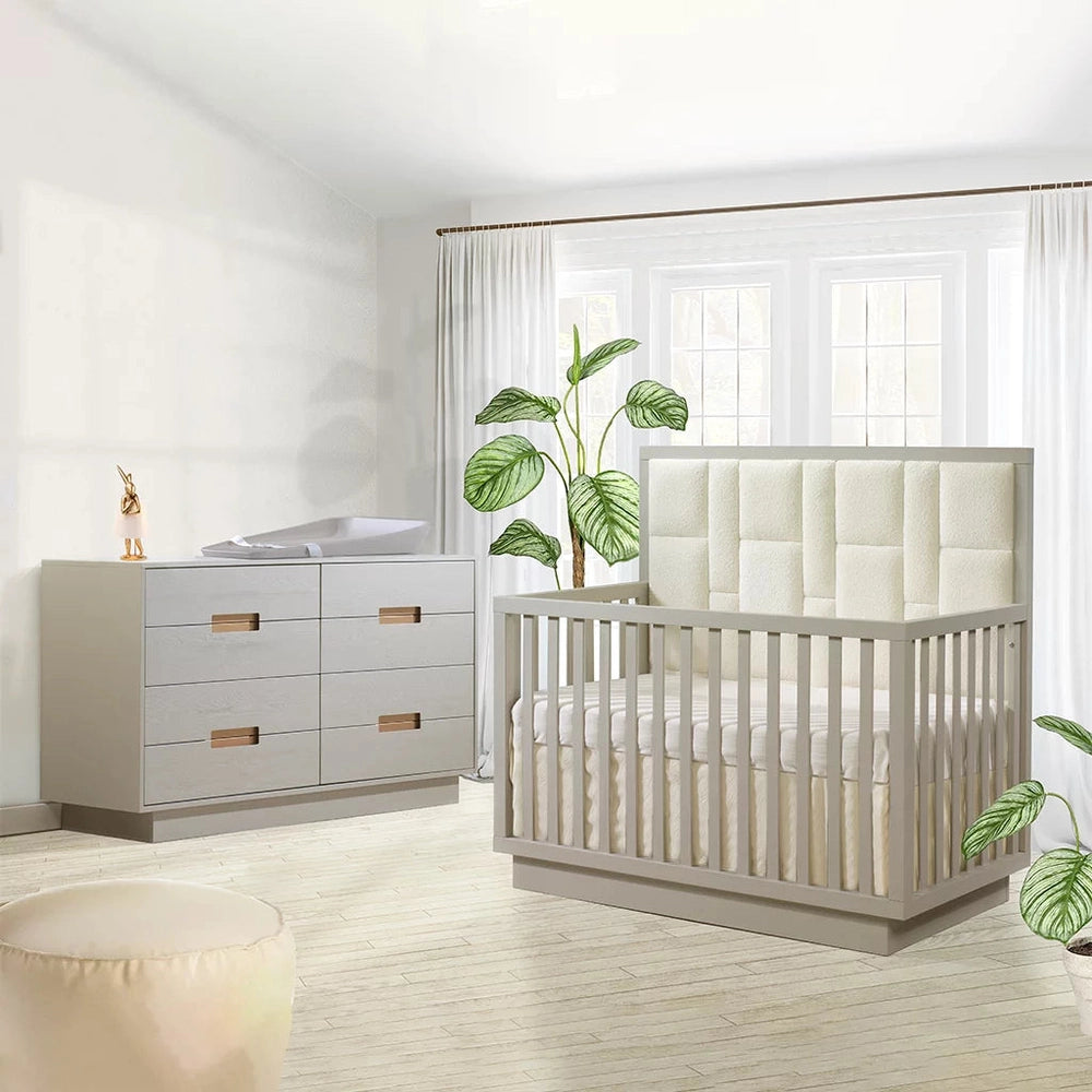 Natart Signature Series Como 8-Drawer 65 Inch King Dresser in pale gray with copper pulls, beside a crib in a bright nursery.
