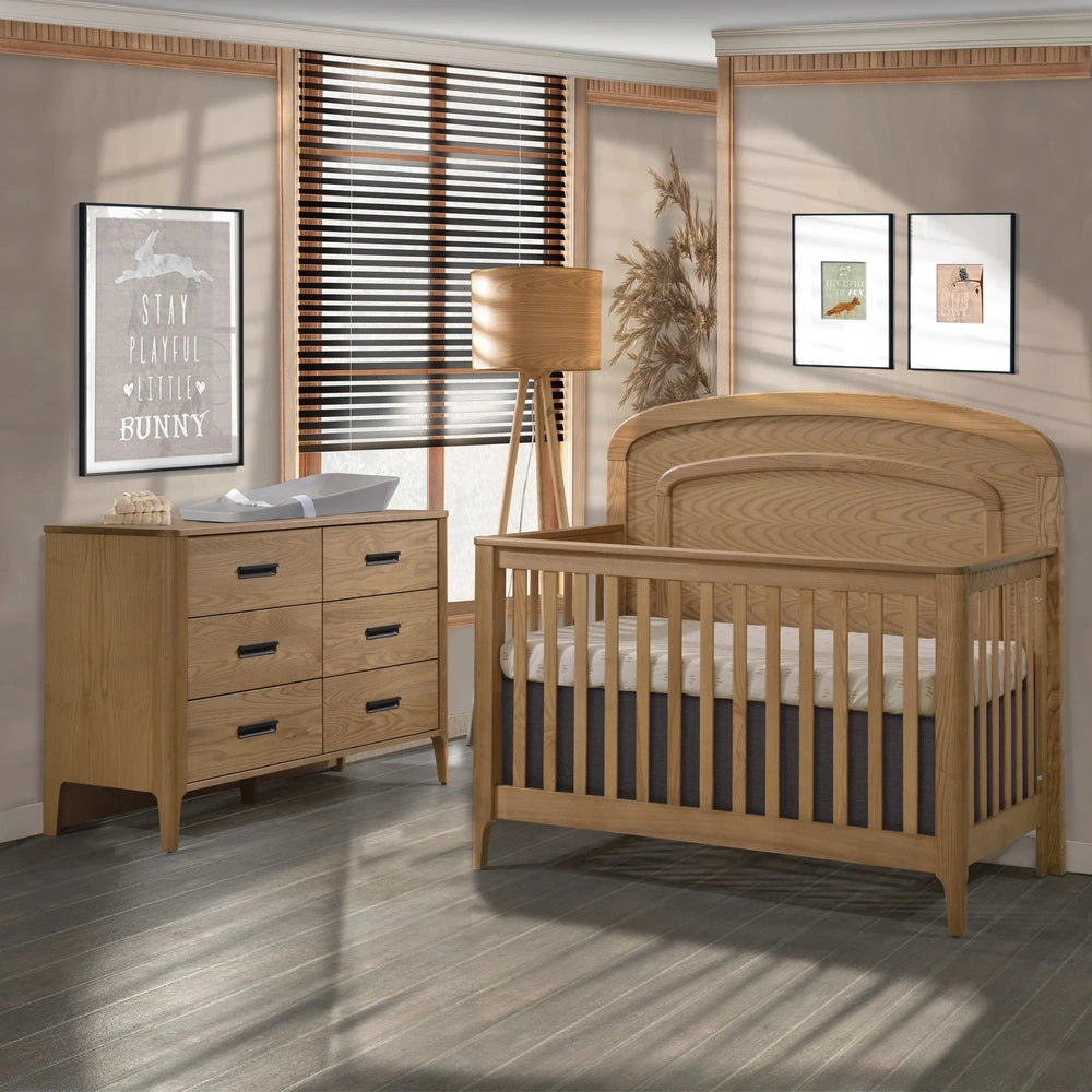 Natart Palo 5-in-1 convertible crib in natural wood with arched molding and matching dresser.