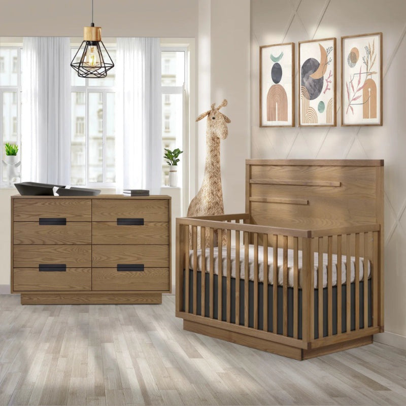 Natart Signature Series Como 8 Drawer 52 Inch Double Dresser in warm wood with black pulls, beside a crib in a peaceful nursery.