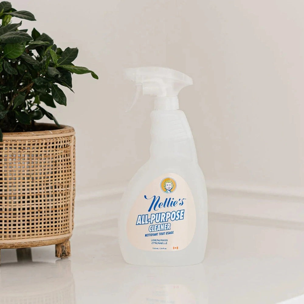 Nellie's All-Purpose Cleaner spray bottle in white plastic (710 ml) stands beside a potted plant.