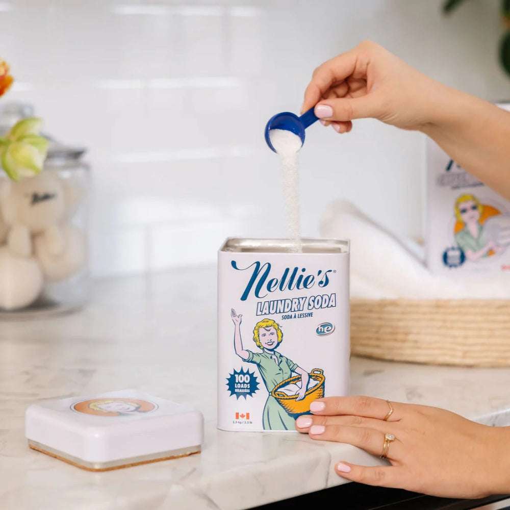 Nellie's Laundry Soda can with blue scoop pouring powder; white retro-style packaging.