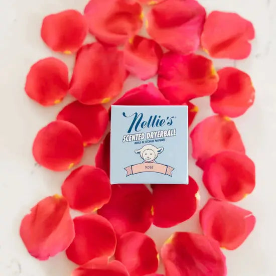 Nellie's Scented Wool Dryerball box sits among pink rose petals, highlighting a scented laundry accessory.